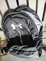 Black Under Armour backpack with visible logo and multiple unzipped compartments to show space inside.