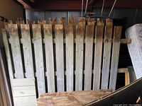 Photo showing several weathered wooden fence panels leaning vertically in storage.