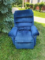 Blue fabric electric recliner chair photographed outside on grass with visible remote control cord on seat.
