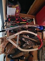 Top view of a box with various missing hand tools including saws, pliers, screwdrivers, welding torch tip or spray hose nozzle, and other assorted tools.