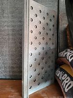 Stacked rectangular metal trays with evenly spaced round holes on the surface