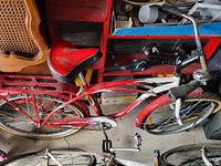 Top and side view of the red bicycle showing the seat, handlebars, frame, wheels, and rear luggage rack.