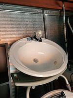 Photo of a white oval bathroom sink with a metal single-handle faucet mounted; visible minor staining on sink basin.