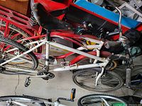 Photo shows a white and red bicycle with a multi-gear setup, rear derailleur, brake levers, and exposed chain. Condition of the bike cannot be confirmed from the image alone.