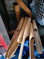 Close up photo showing seven hollow wooden tubes cut at an angle for wind chimes. They appear used with natural discoloration on the wood.