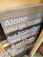 Photo showing wooden sign with inspirational quote painted in white over horizontal slats with different wood tones