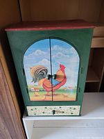 Front view of wooden storage cabinet with painted rooster on door