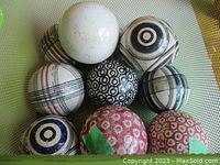 Top view of 11 carpet bowls balls in a basket, some marked with green tape indicating chip damage.