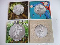 Four $20 silver coins displayed in presentation folders showing front designs of Wolf, Bugs Bunny, T-Rex, and Superman.