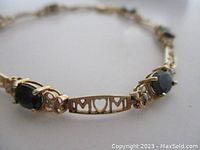 Bracelet close-up showing oval onyx stones, diamond accents and “MOM” cut-out plaque