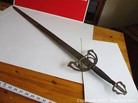 Full view of sword laid flat showing blade, guard and grip