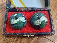 Top view of two cloisonne balls with crane and turtle designs in red felt-lined box