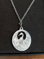 Close-up image of the silver plated round medallion pendant with crane motif showing detailed engravings.