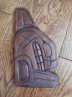 Front view of the wood carved killer whale showing detail and finish on a hardwood floor.