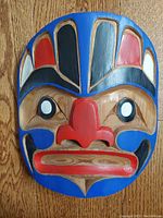 Front view of Northwest Coast Indigenous vintage cedar mask showing vibrant painted design in blue, red, black, and white.