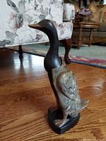 Duck-shaped Bakelite figurine standing on a wood floor, showing detailed marbled texture on the body with black neck and beak.