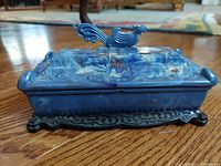 Front view of the vintage blue marbled Bakelite box with dragon carvings and phoenix lid handle on ornate black base.