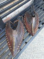 Pair of leather tapaderos displayed on bench, top-down view