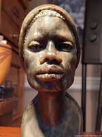 Frontal close-up view of stone bust showing facial features and headscarf detail.