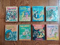 Eight vintage Big Little Books arranged in two rows on a wooden surface showing titles and cover illustrations.