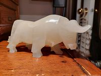 Side view of white translucent onyx bull sculpture on wooden surface