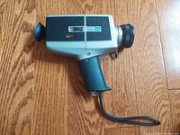 Side view of the Vivitar 84P silent Super 8 movie camera showing pistol grip, wrist strap, and lens.