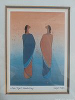 Framed lithograph artwork 'Where Night Meets Day' showing two stylized figures in robes against gradient backdrop, signed by artist Ioyan Mani.