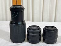 Three Minolta lenses arranged side by side, showing relative sizes and controls.