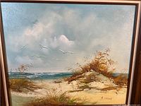 Close-up of the beach painting showing sand dunes, grasses, ocean, sky, seagulls, and the artist's signature 'S. Willis'.