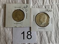 Front view of two coins in white cardboard holders, Washington quarter and Kennedy half dollar both dated 1969 with 'D' mint mark, placed on fabric background with number 18.