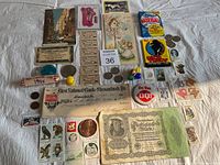 Overview of all items laid out on cloth including bands of coins, stamps, cards, bank check, pins, and a large green certificate.