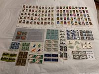 Photo showing an assortment of stamp sheets and blocks, including birds, flowers, trains, historical figures, and other designs.
