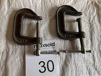 Two small metal C-clamps placed side by side with a MaxSold bidding number 30 visible.