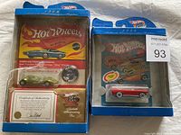 1969 California Custom Johnny Lightning replica car in sealed packaging with certificate of authenticity and pin and 1984 Hot Wheels car in blue packaging