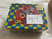 Top view of Looney Tunes metal tin with colorful polka dots and characters, with a paper tag '44'.
