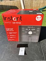 Front left angled view of unopened boxed Instant Vortex air fryer showing brand, model, and main features.