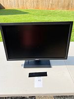 Front view of Dell monitor on a table outdoors with black screen off.