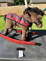 Full side view of the brown plush horse rocker with wooden rockers and plaid saddle, showing overall condition and design.