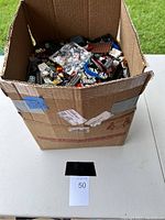 Front view of cardboard box filled with assorted LEGO pieces