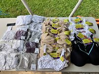 Overview showing nursing bras in nude, white with black dots, black with turquoise accent, purple and additional bras, plus folded assorted maternity pants including a leopard print pair.