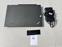Closed Lenovo ThinkPad laptop with power adapter placed on a table.