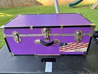 Front view of large purple chest showing its metal trim, latches, handle, and American flag decal