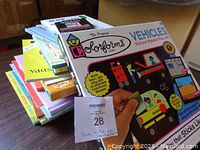 Stack of colorful children's books and Vehicles Picture Panels Play Set in box.
