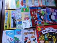Overview shot showing multiple children's books including Thomas & Friends, All Dogs Go to Heaven, Prince & Pauper, and a Firefighter book.