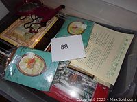 Photo of multiple cross-stitch kits still in original packaging with printed designs and accompanying instructions.