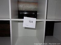 Close-up view of cubby compartments showing interior and shelf structure, with a small note labeled '104' inside the center cubby.