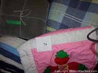 Photo showing folded gray blanket, blue plaid comforter, striped blue blanket, and corner of handmade quilt with floral appliqué and white border.