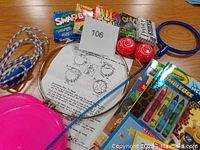 Photo of assorted games in boxes, yo-yos, jump rope, speedring, and frisbees on wood table.
