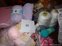Photo of the yarn balls and cones in various colors including lavender, pink, white, and turquoise with other kit materials.