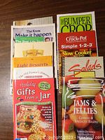 Close-up view of several colorful cookbooks including holiday gifts, slow cooker recipes, jams & jellies, salads and light desserts.
